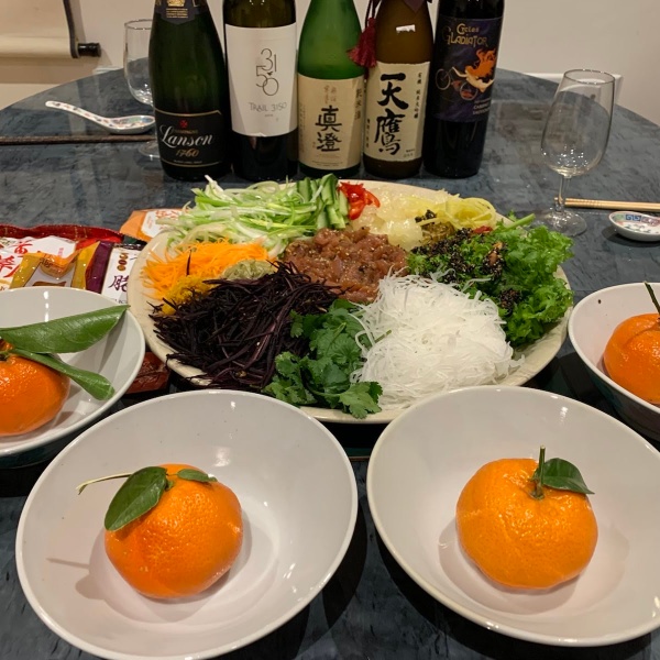 Image of Yee Sheng "Prosperity Toss Salad" with bottles of sake